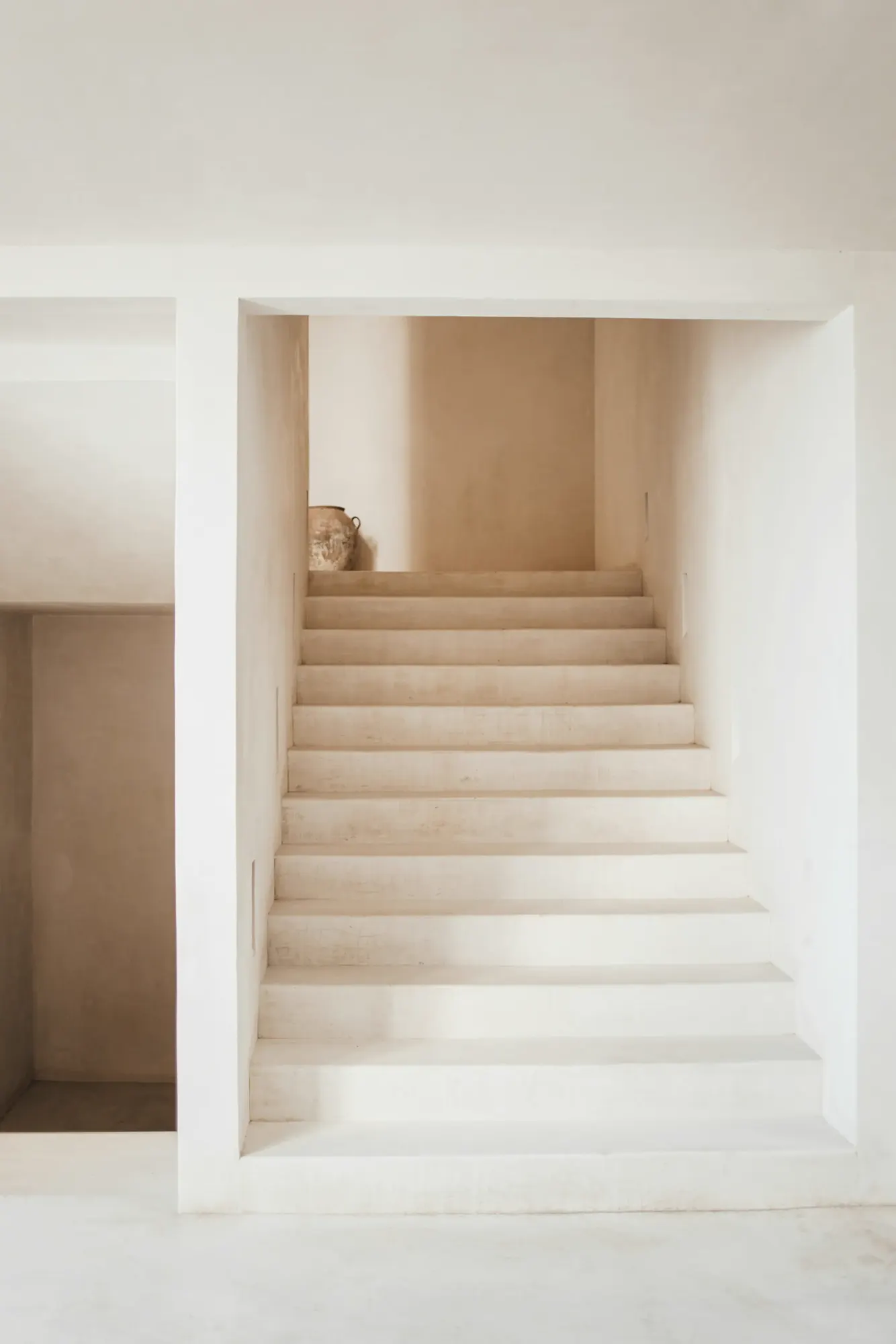 Una escalera clara entre muros blancos y lisos