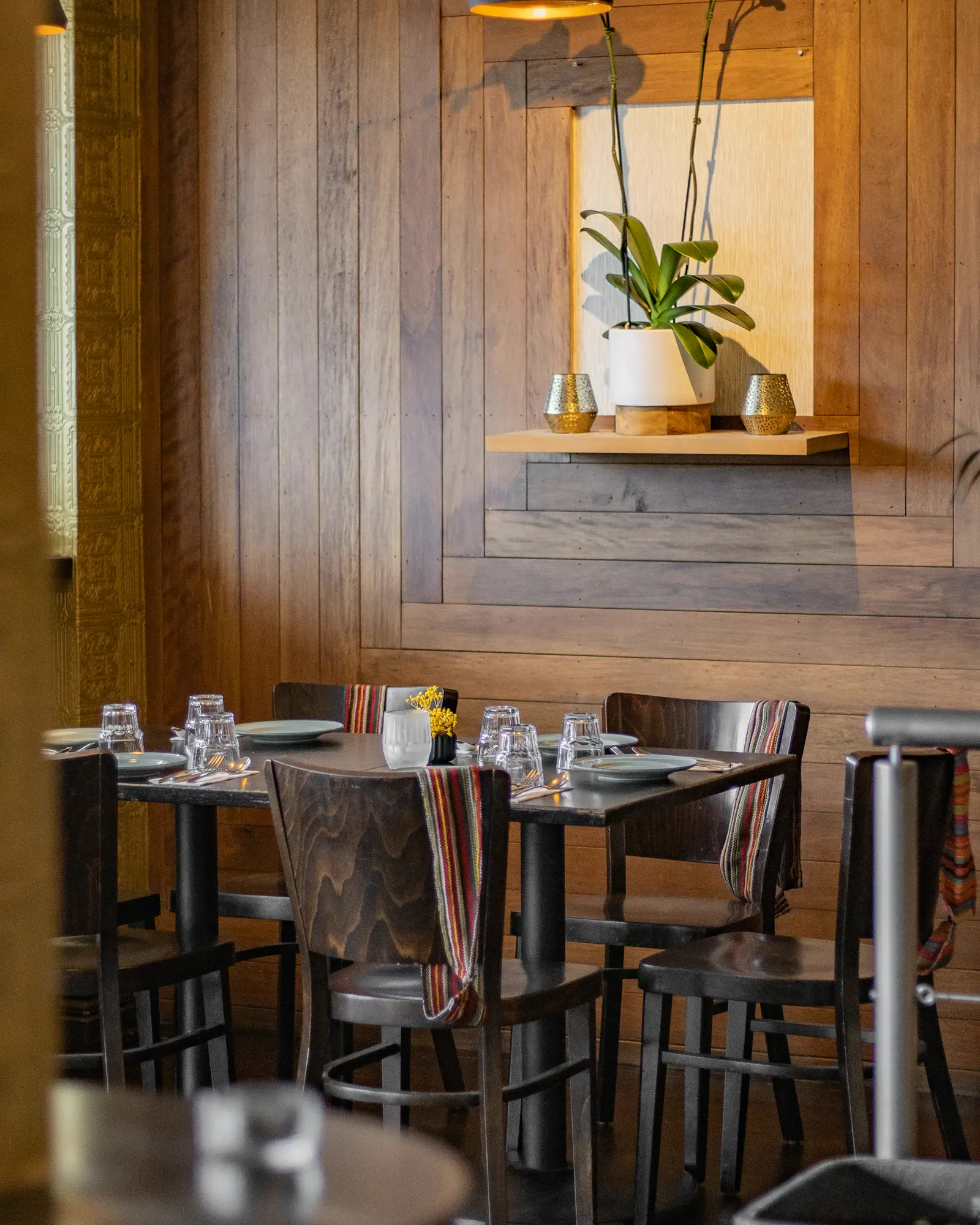 El comedor: paredes de madera, sillas oscuras y mesas puestas