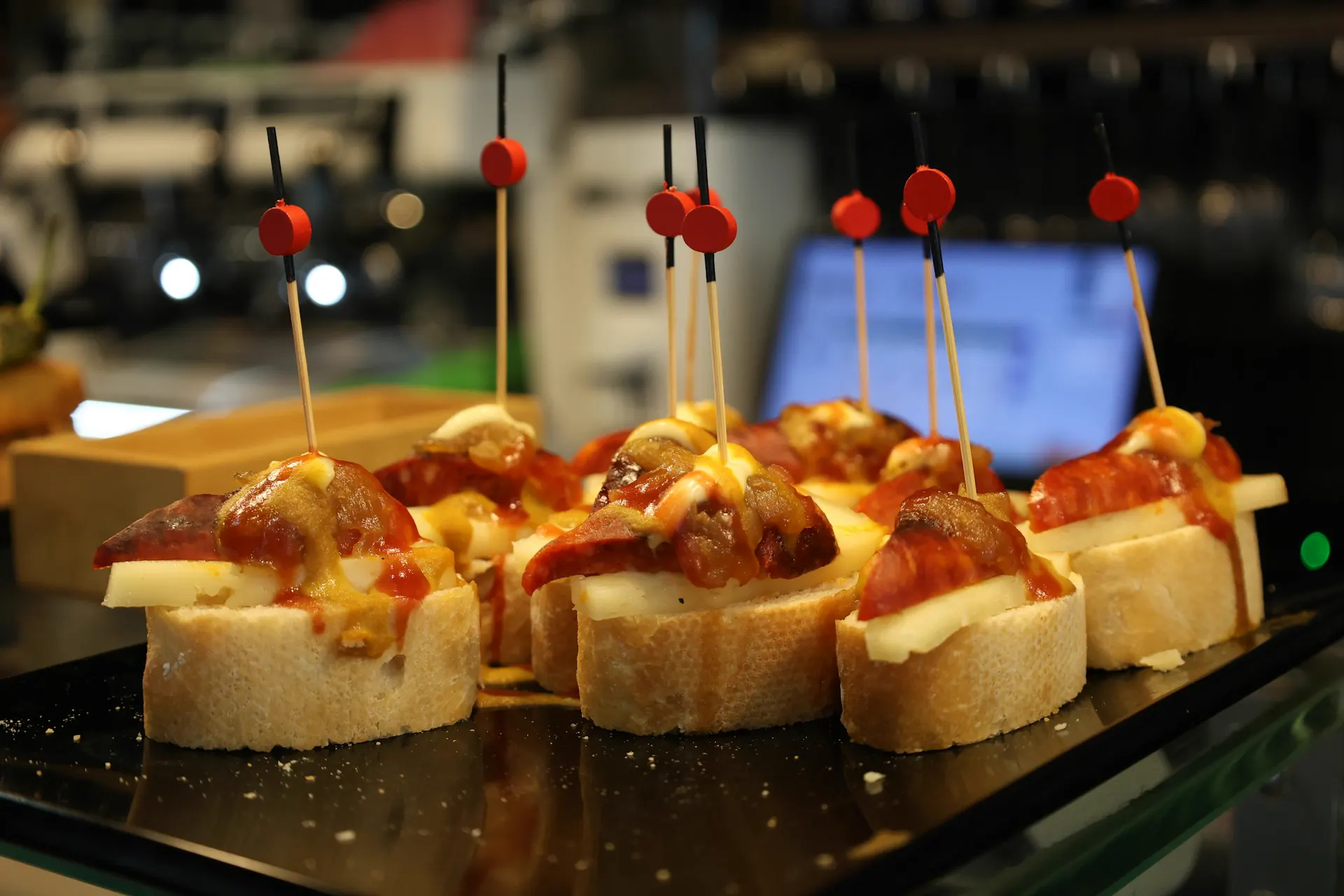 Pintxos sobre pan con palillos, con pimientos y jamón